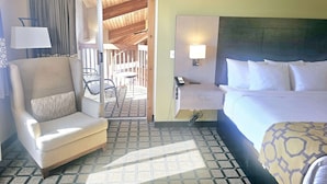 A hotel room with a bed, a chair, a desk with a lamp, and a view of the outdoor area. - Baymont by Wyndham Rolla (Rolla)