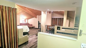 A room with a wooden ceiling, a sofa, a dining table, and a mirror. - Baymont by Wyndham Rolla (Rolla)