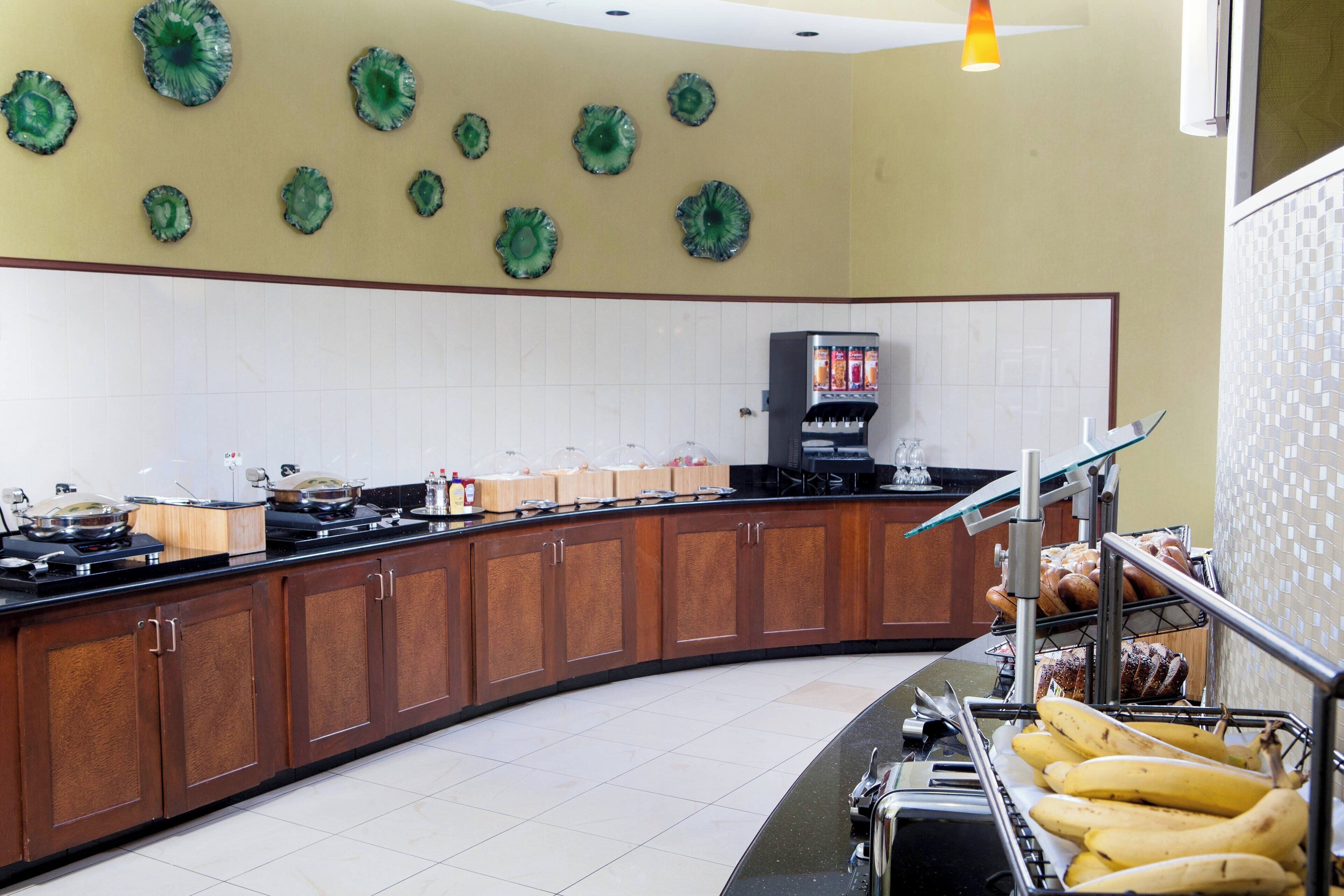 A kitchen with a curved counter, wooden cabinets, and a coffee machine.