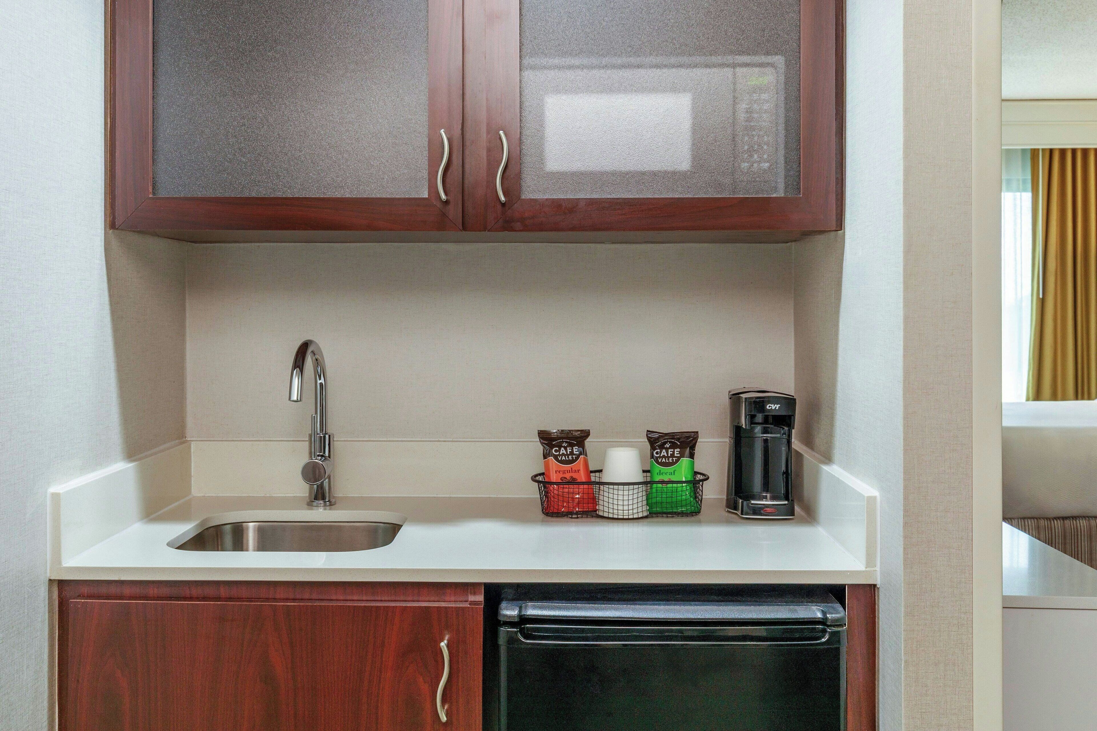 A kitchen with a sink, a coffee maker, and a dish rack.