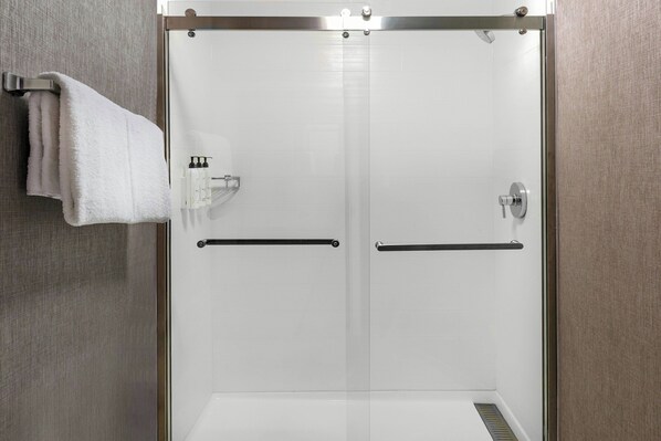 Une cabine de douche moderne dotée d’une porte en verre, d’un porte-serviettes et d’un sèche-mains.