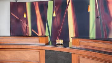 A reception desk with a modern design, featuring a wooden finish and a black countertop.