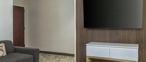Una sala de estar moderna con un televisor de pantalla plana montado en una pared de madera, un sofá gris y una consola blanca.