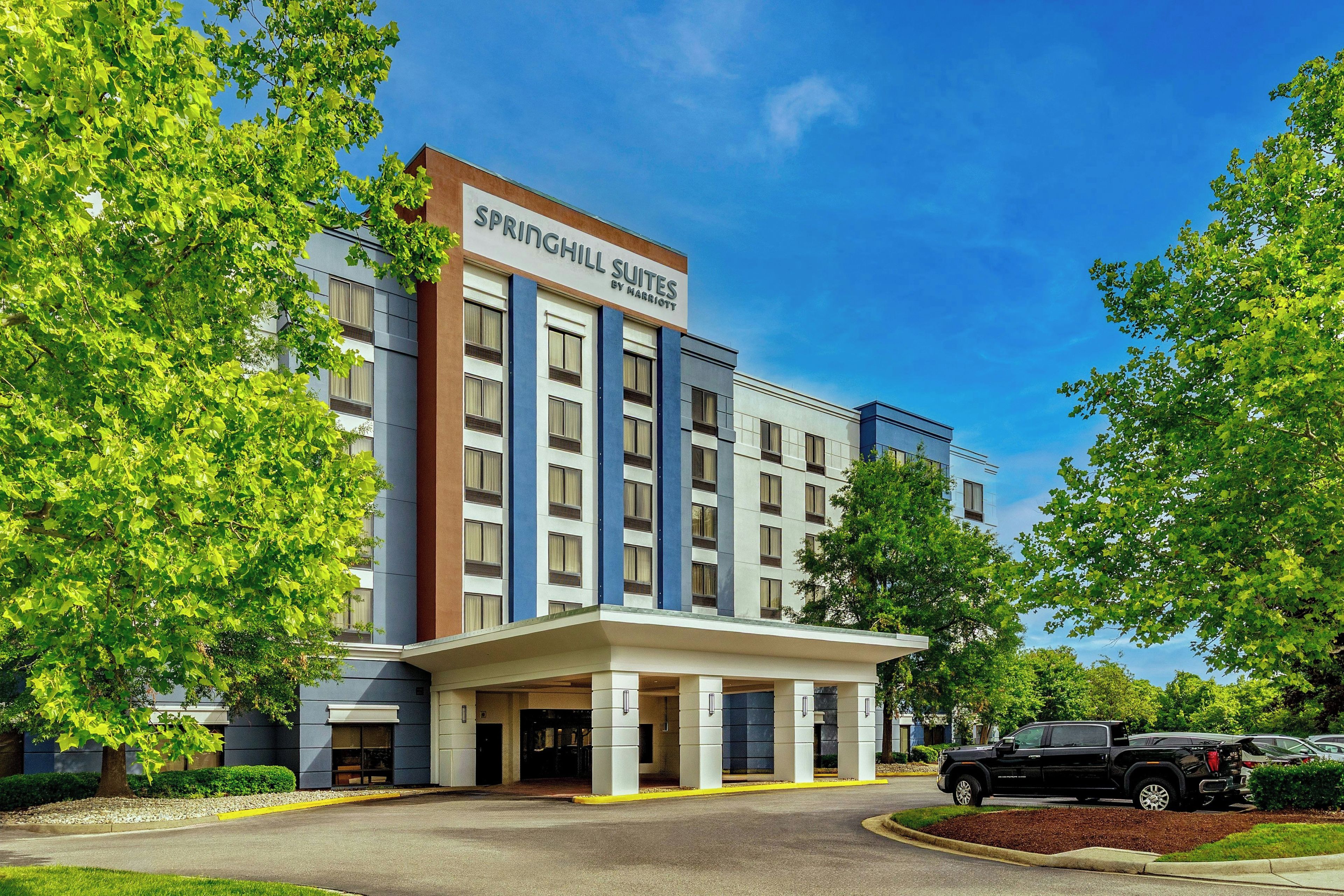 Un hôtel moderne, facilement reconnaissable grâce à son enseigne bien visible indiquant « Springhill Suites by Marriott », avec une architecture à plusieurs étages, un toit plat et une entrée abritée.