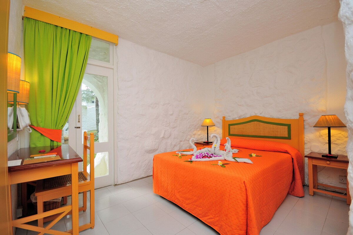 Une chambre d’hôtel avec un lit, un bureau, une chaise et une fenêtre avec des rideaux.