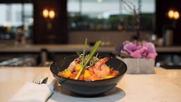 A bowl of food on a table with a napkin and utensils beside it.