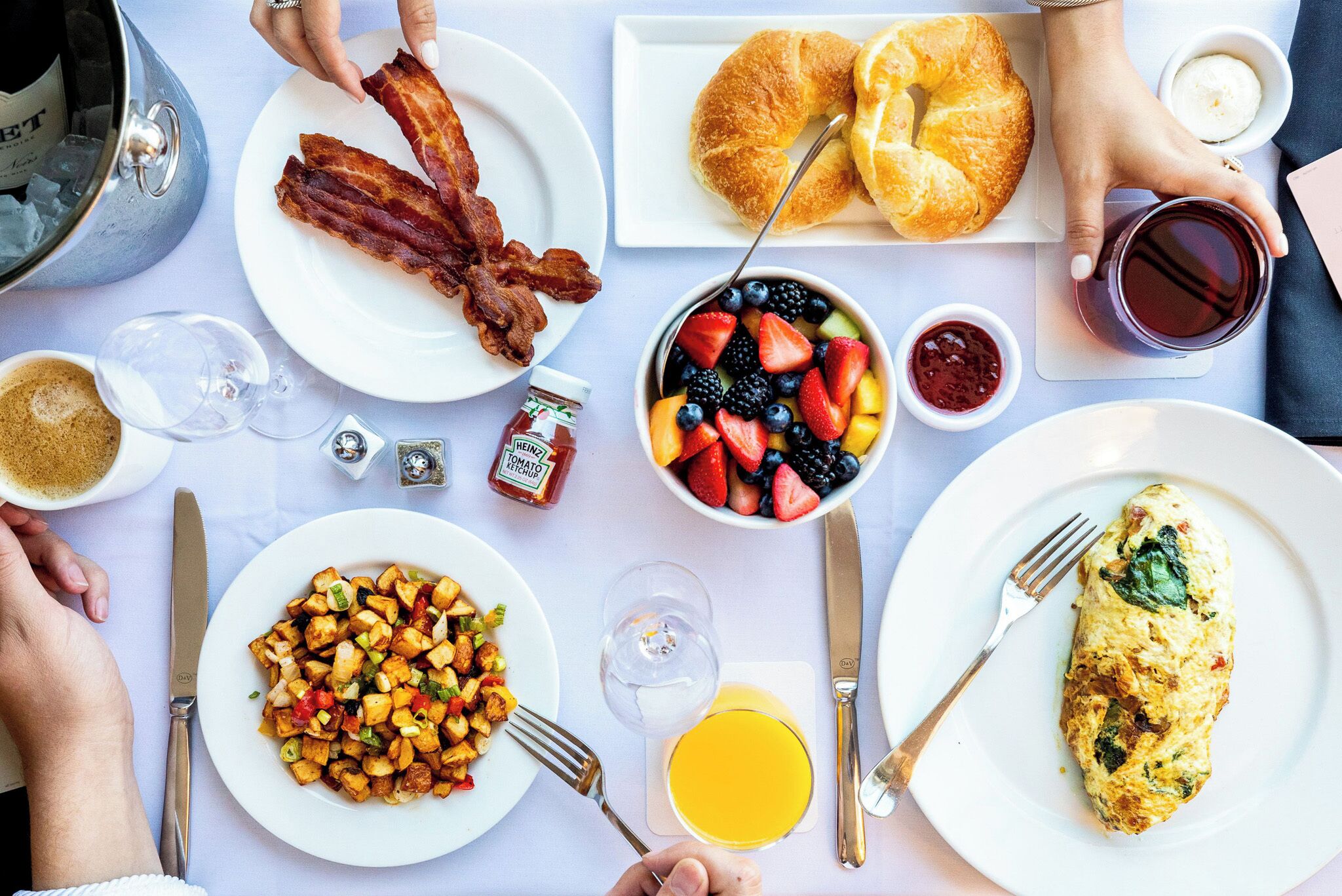 Een ontbijttafel met spek, eieren, toast en fruit.
