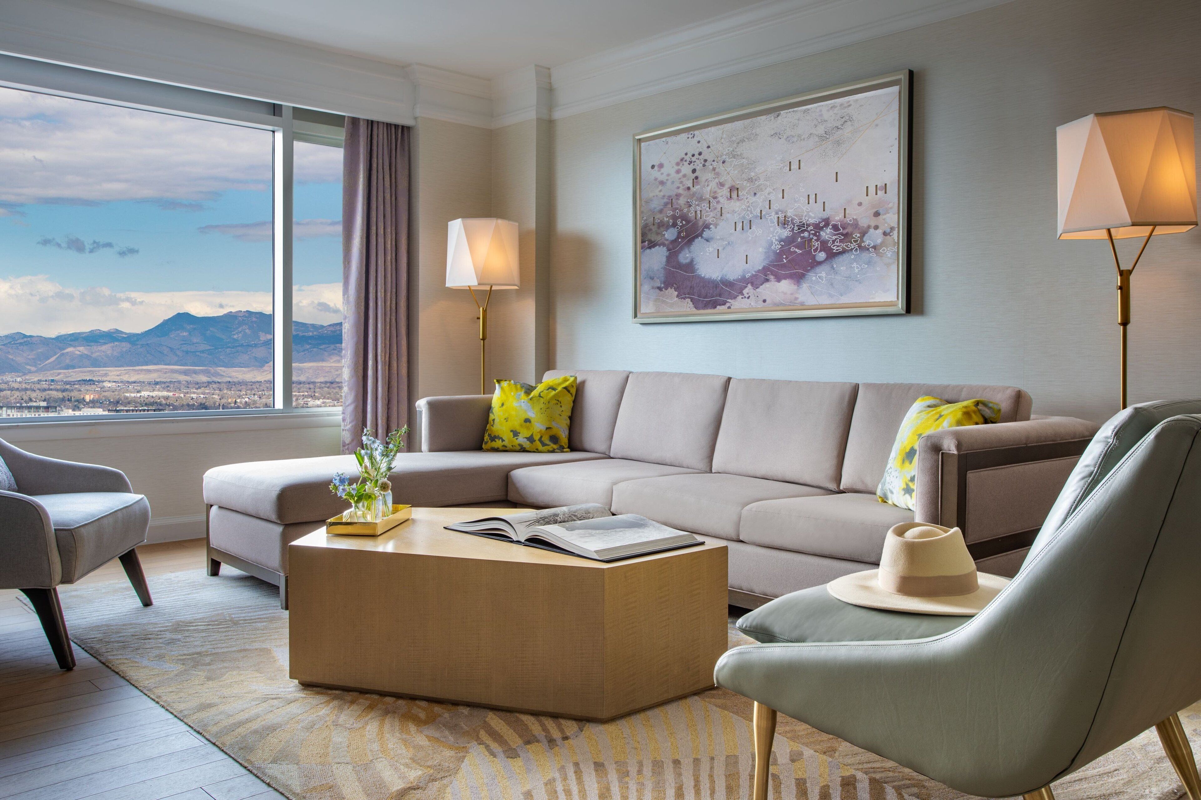 A modern living room with a large window, a sofa, a coffee table, and two lamps.
