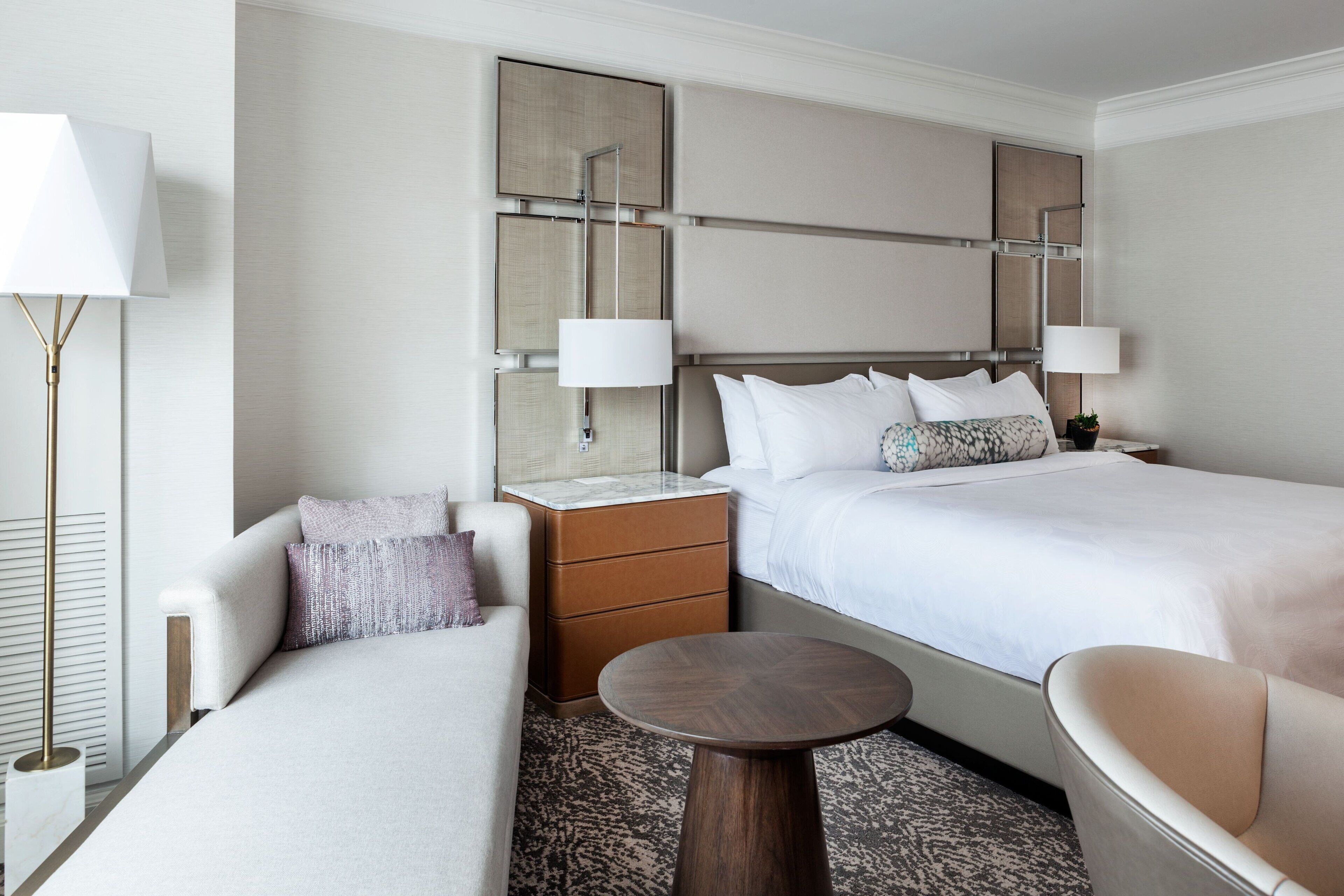 Une chambre d’hôtel avec deux lits, un canapé, une petite table et une table de chevet.
