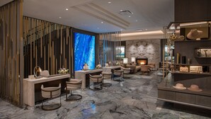 En moderne lobby med marmorgulv, receptionsdisk, siddeområde og pejs.
