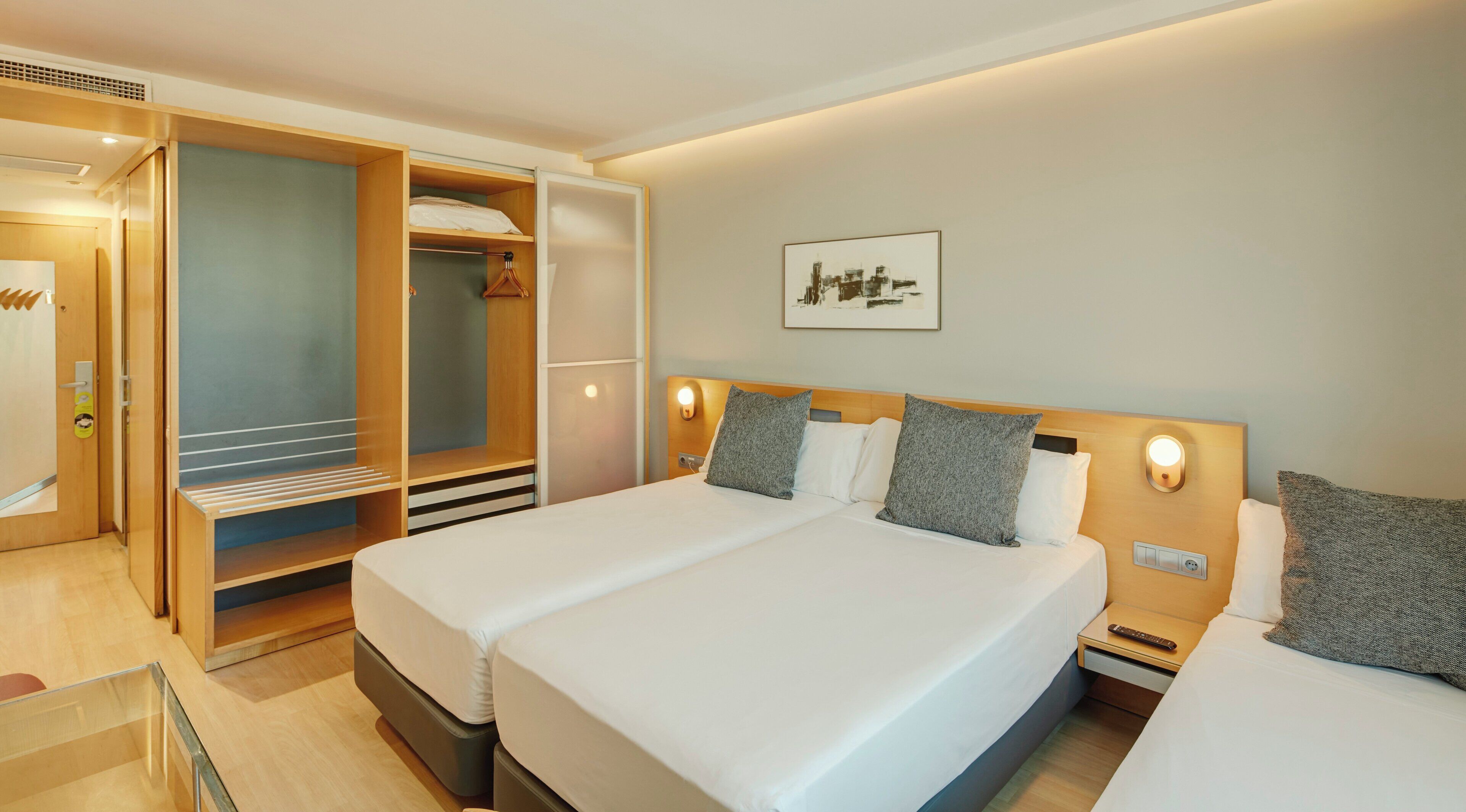A hotel room with a bed, bedside tables, a wardrobe, and a framed picture on the wall.