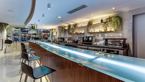 Een moderne bar met een glazen toonbank, barstoelen en een koffieapparaat.
