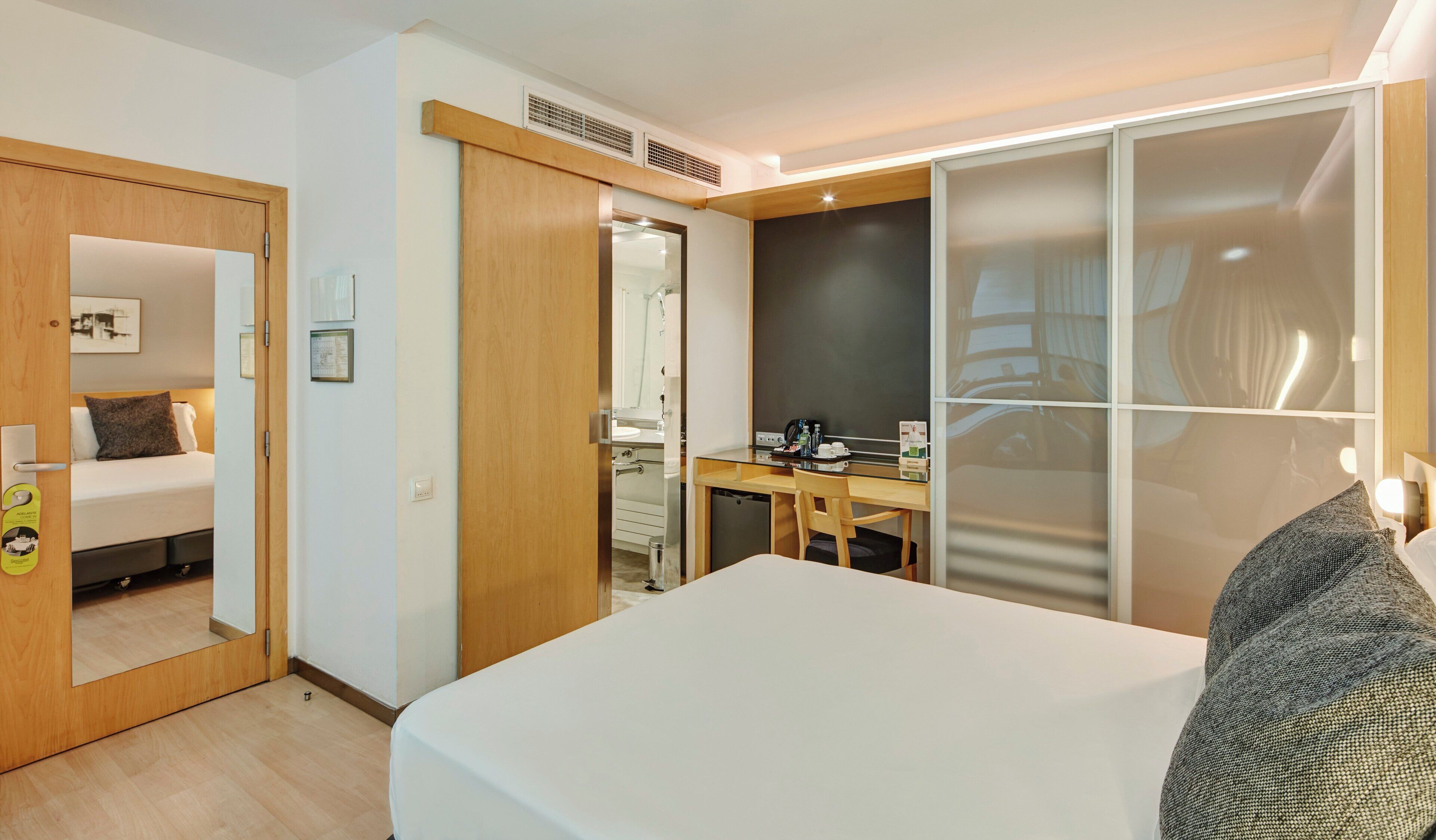 Een hotelkamer met een bed, een bureau, een stoel, een spiegel en een kledingkast.