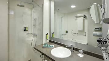 A modern bathroom with a glass shower enclosure, a white sink, and a large mirror.