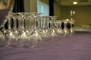 Uma mesa com vários copos de vinho de vidro transparentes dispostos em fileiras.