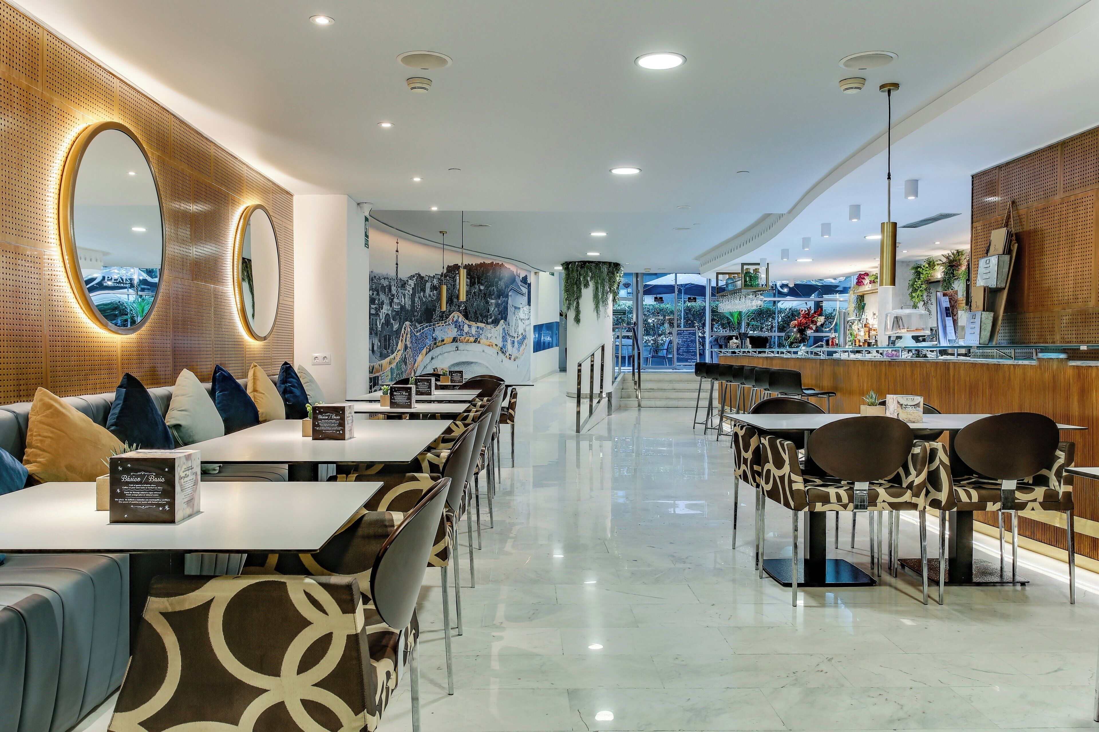 Un restaurante moderno con una barra alargada, zona de asientos con sillas estampadas y un mural en la pared.