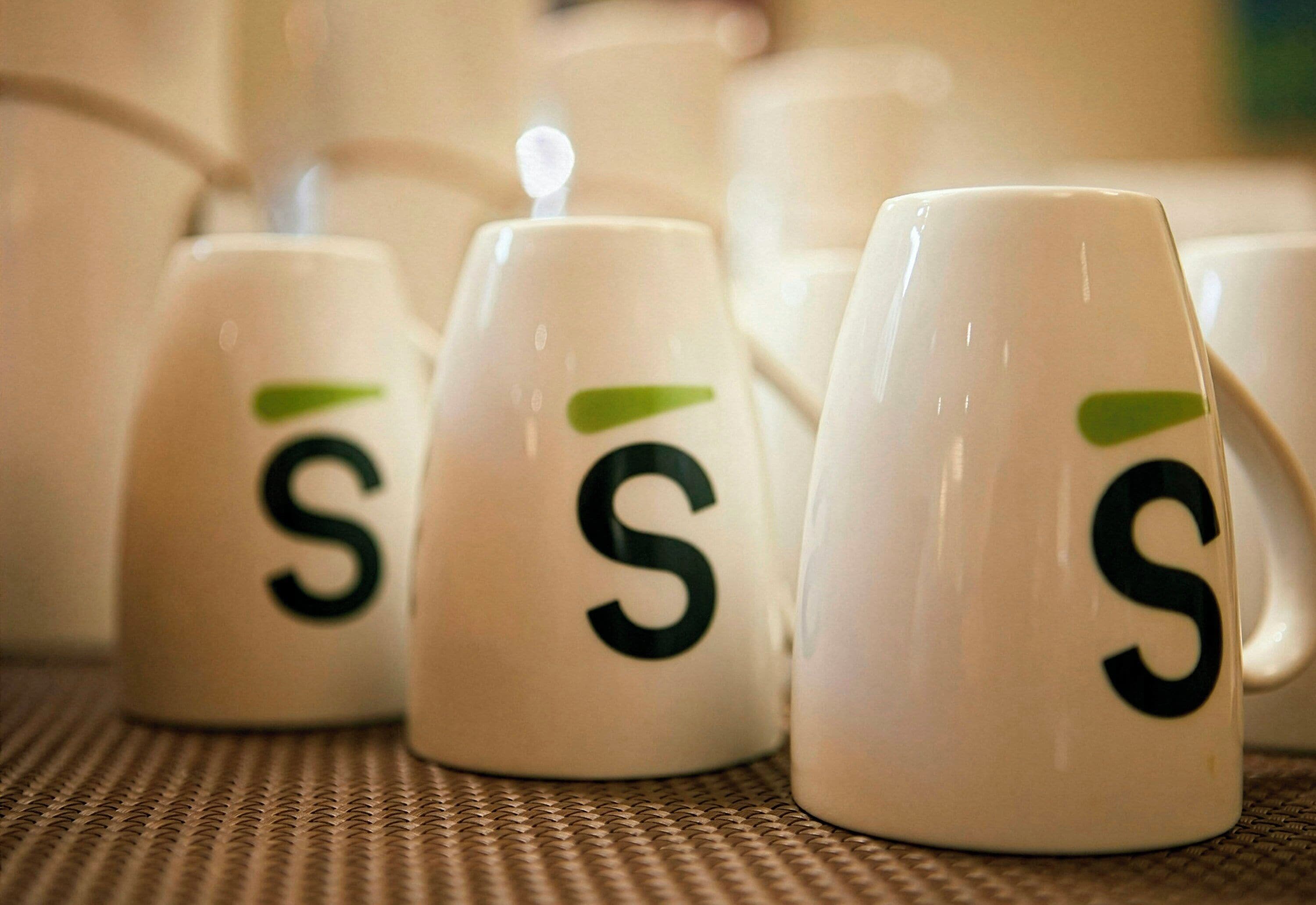 Una hilera de tazas blancas con un logotipo verde y la letra 'S'.