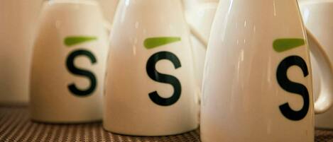 Una hilera de tazas blancas con un logotipo verde y la letra 'S'.