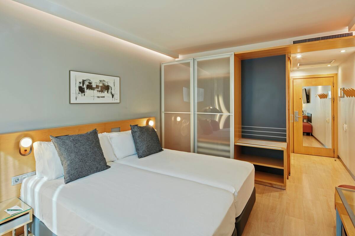 Une chambre d’hôtel comprenant un lit, une table de chevet et une armoire avec un miroir.