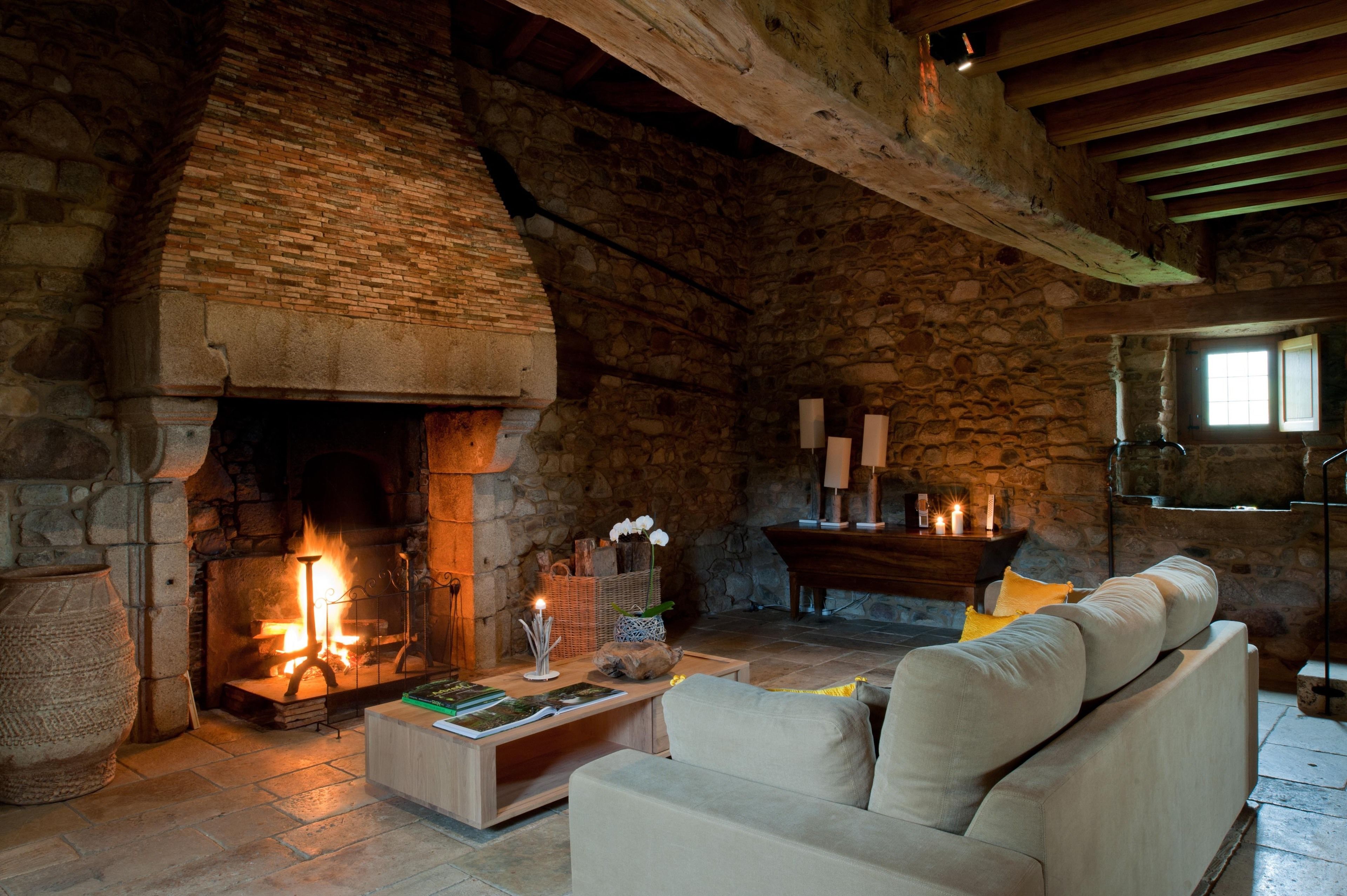 A cozy room with a stone fireplace, a wooden ceiling, and a comfortable sofa.