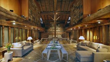 A spacious hall with stone flooring, wooden beams, and a central table set for dining.