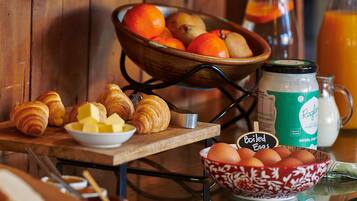 A breakfast setup with croissants, eggs, and a bowl of fruit.