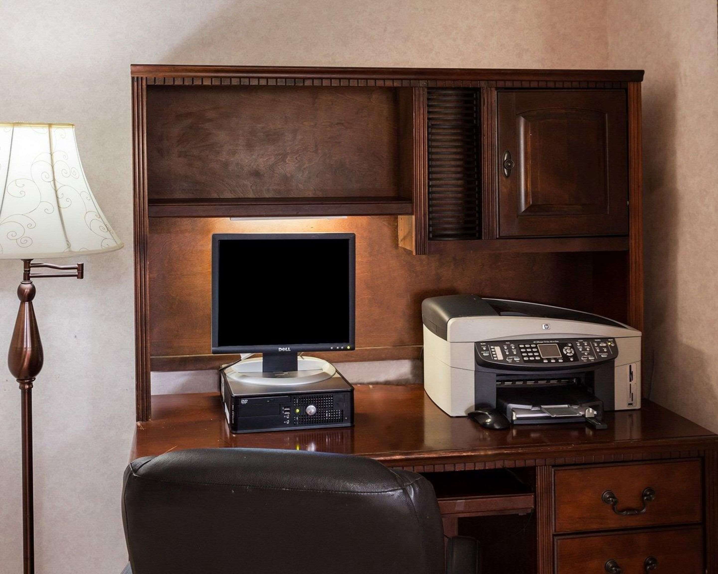 A wooden desk with a Dell monitor, HP printer, and a lamp.