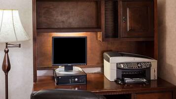 A wooden desk with a Dell monitor, HP printer, and a lamp.