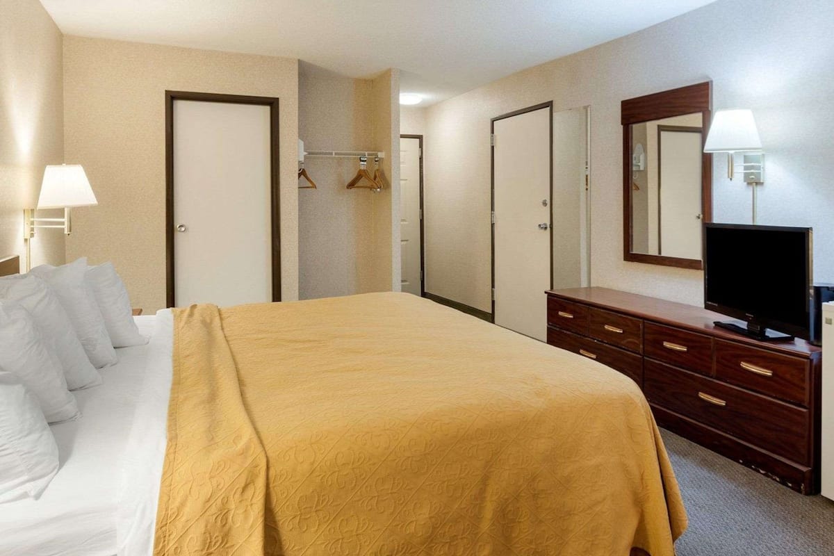 A hotel room with a bed, a dresser, a television, and a wardrobe.