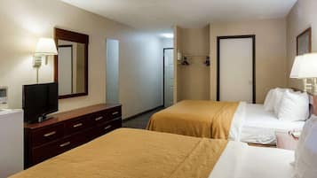 A hotel room with two beds, a TV, a dresser, and a mirror.