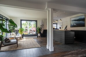 A spacious room with a large window, a surfboard, a desk, and a chair. - Tofino Resort & Marina (Tofino)