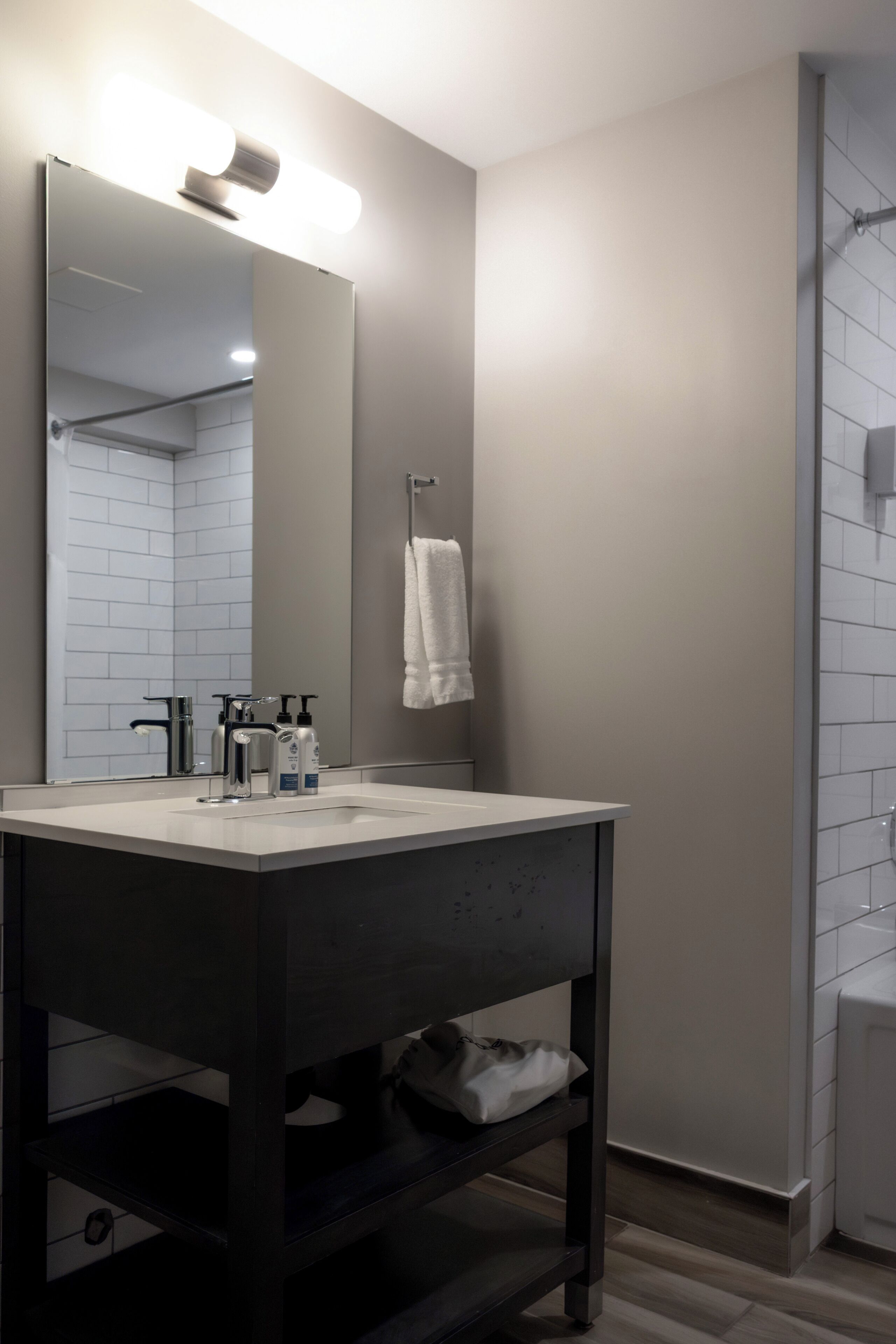 Un baño moderno con un espejo grande, un lavabo blanco y un perchero para toallas.