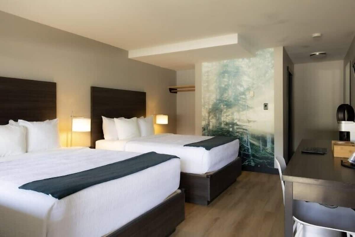 Een hotelkamer met twee bedden, een bureau en een groot raam.