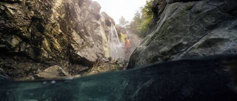 A rocky landscape with a waterfall and a person standing near it.