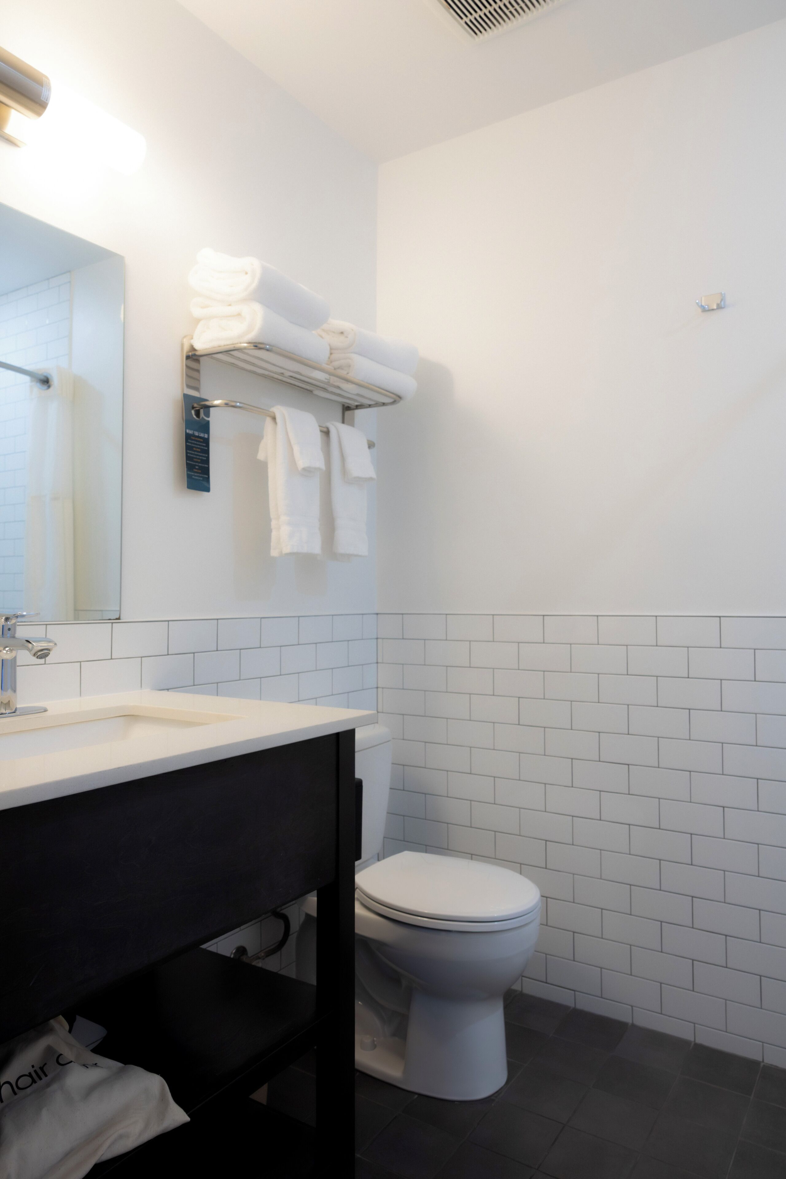 Een badkamer met een witte wastafel, toilet en een handdoekrek met opgevouwen handdoeken.