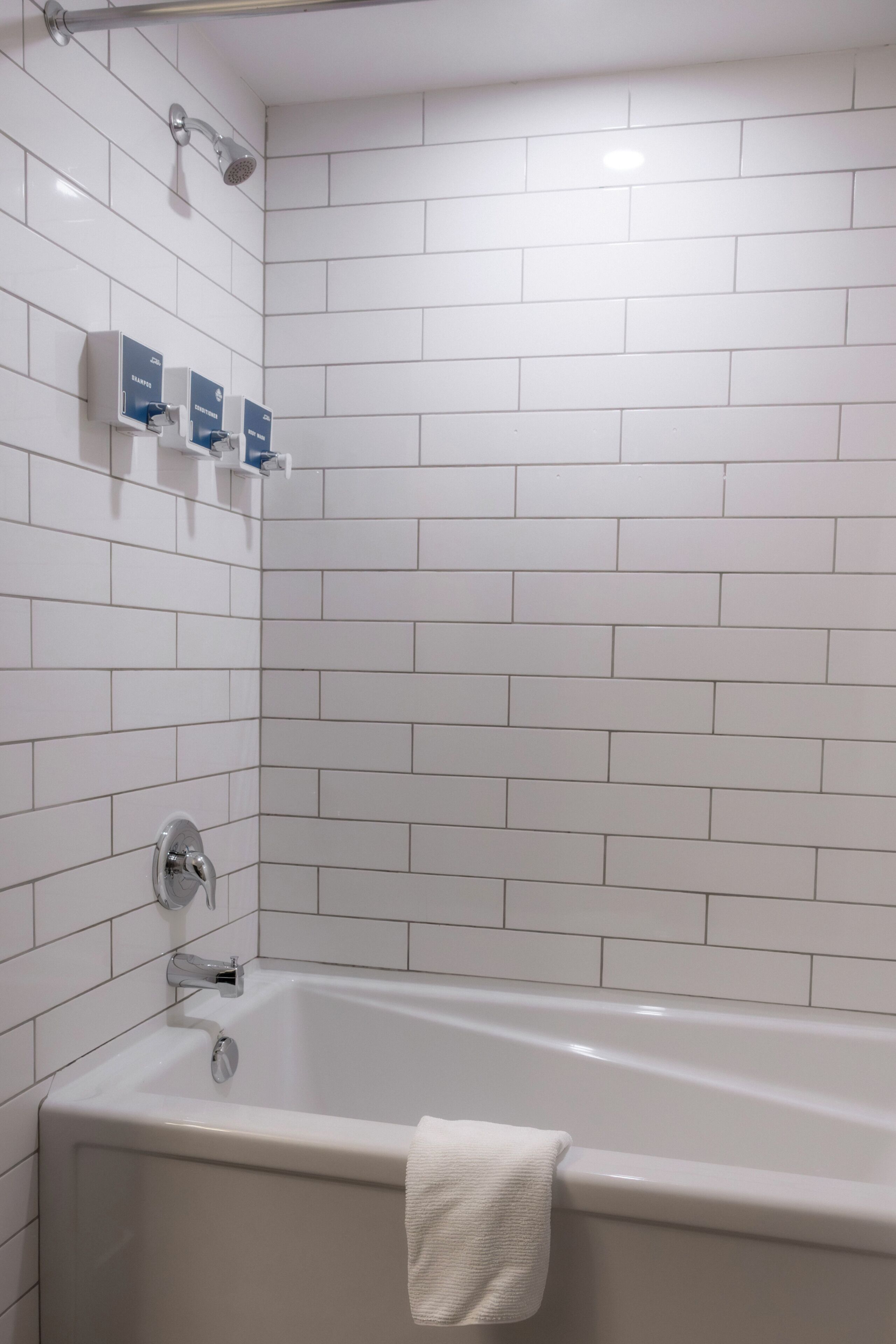 A bathroom with a bathtub, a showerhead, and a hand dryer.