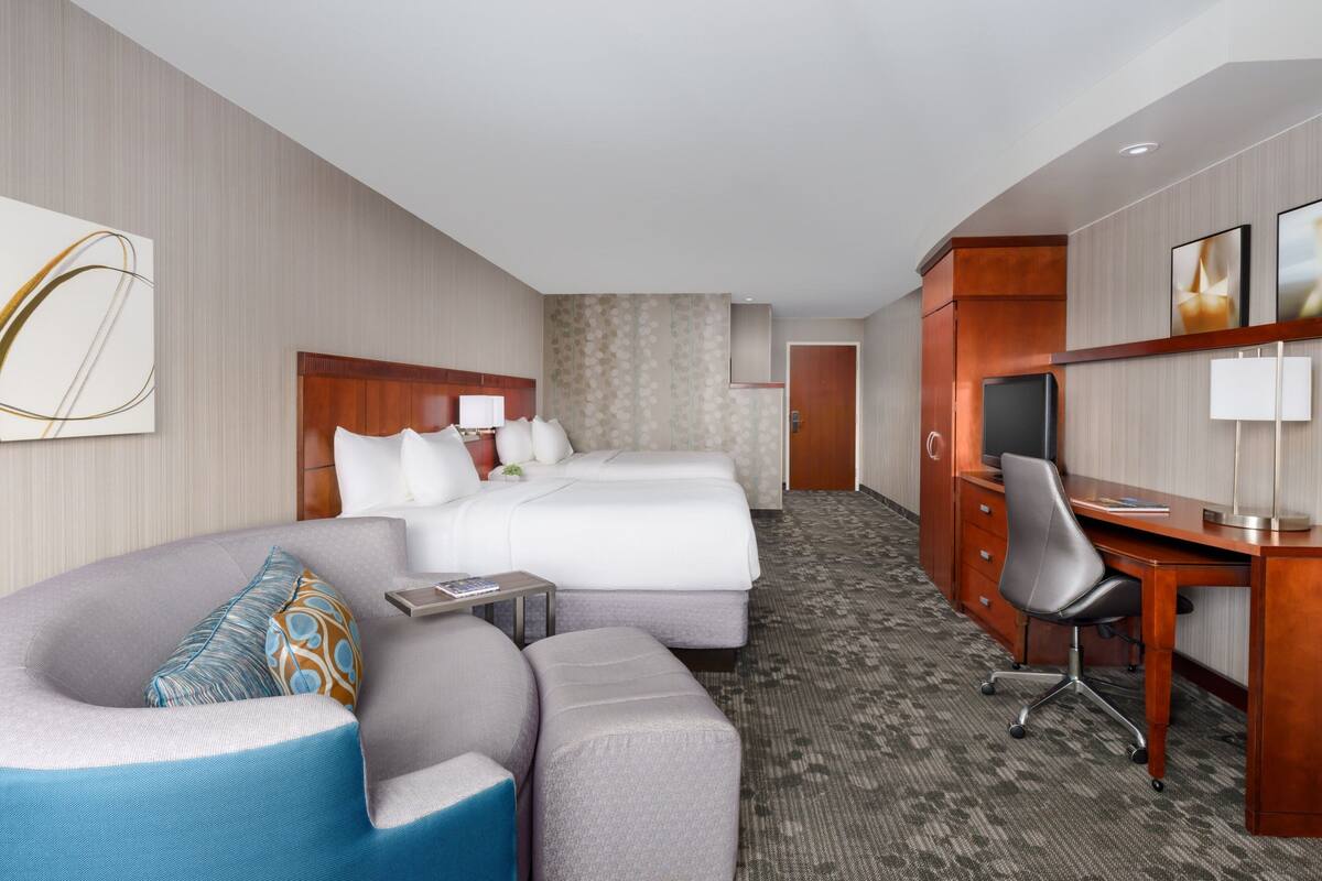 A hotel room with a large bed, a desk, a chair, and a sofa.