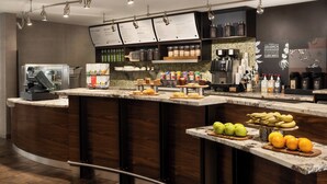 Un caffè moderno con un bancone in marmo, diverse macchine da caffè e una lavagna con il menu.