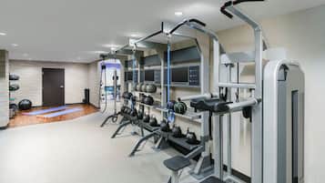 A modern gym with various exercise equipment, including kettlebells, a pull-up bar, and a bench press.