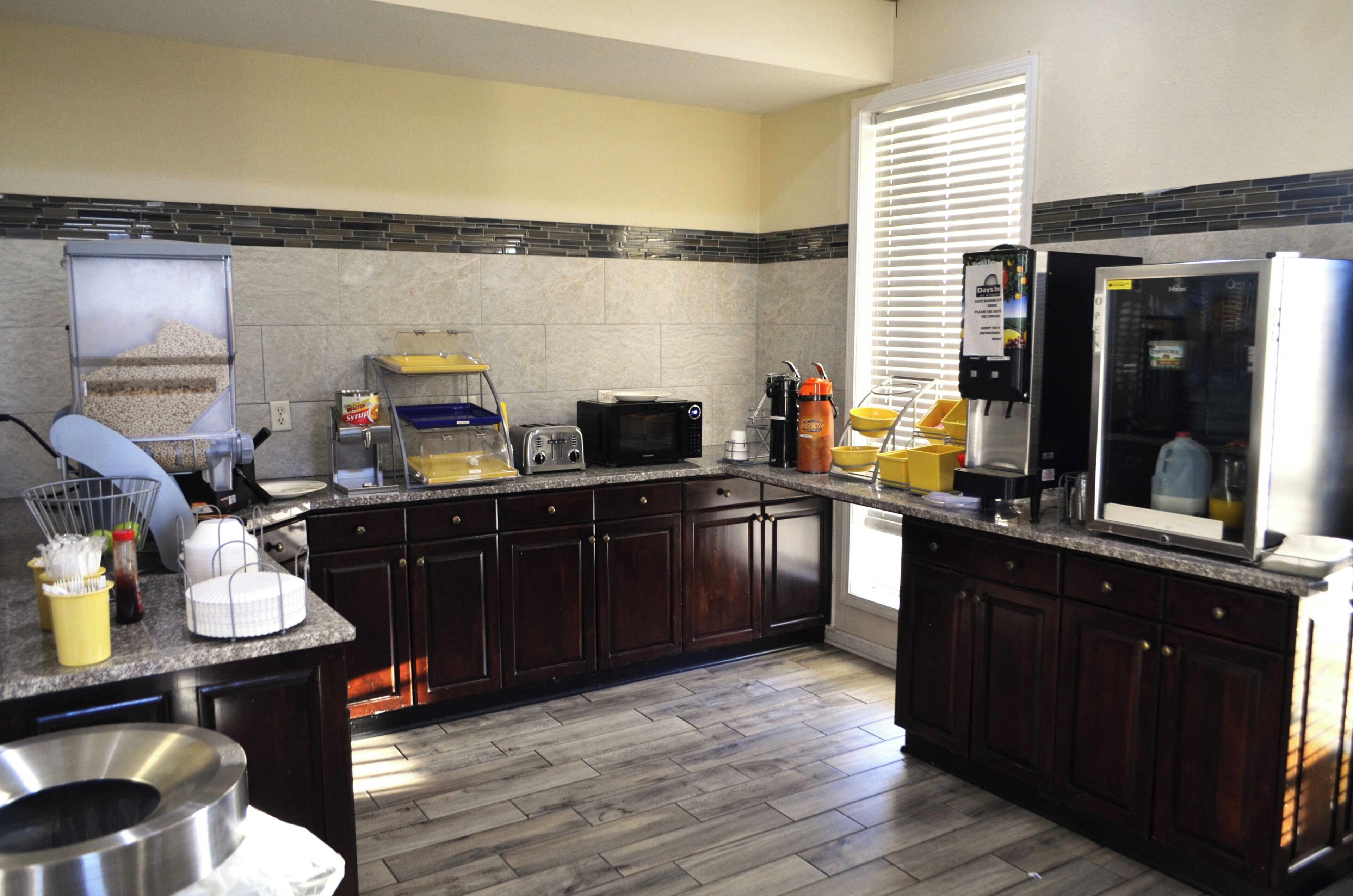 A modern kitchen with dark wood cabinets, granite countertops, a built-in microwave, and a refrigerator.