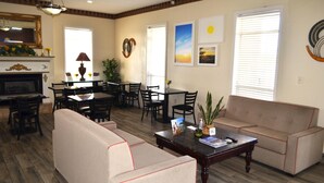 A living room with a sofa, coffee table, dining table, chairs, and a fireplace. - Days Inn by Wyndham Trumann AR (Trumann)
