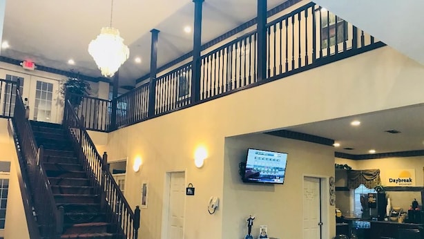 A hotel lobby with a staircase, a reception desk, and a television screen. - Days Inn by Wyndham Trumann AR (Trumann)