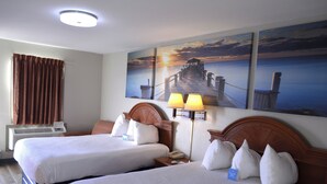 A hotel room with two beds, a nightstand, a lamp, and a painting of a pier. - Days Inn by Wyndham Trumann AR (Trumann)