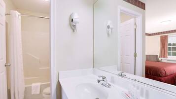 Un bagno con lavandino bianco, specchio e due asciugacapelli montati a parete.