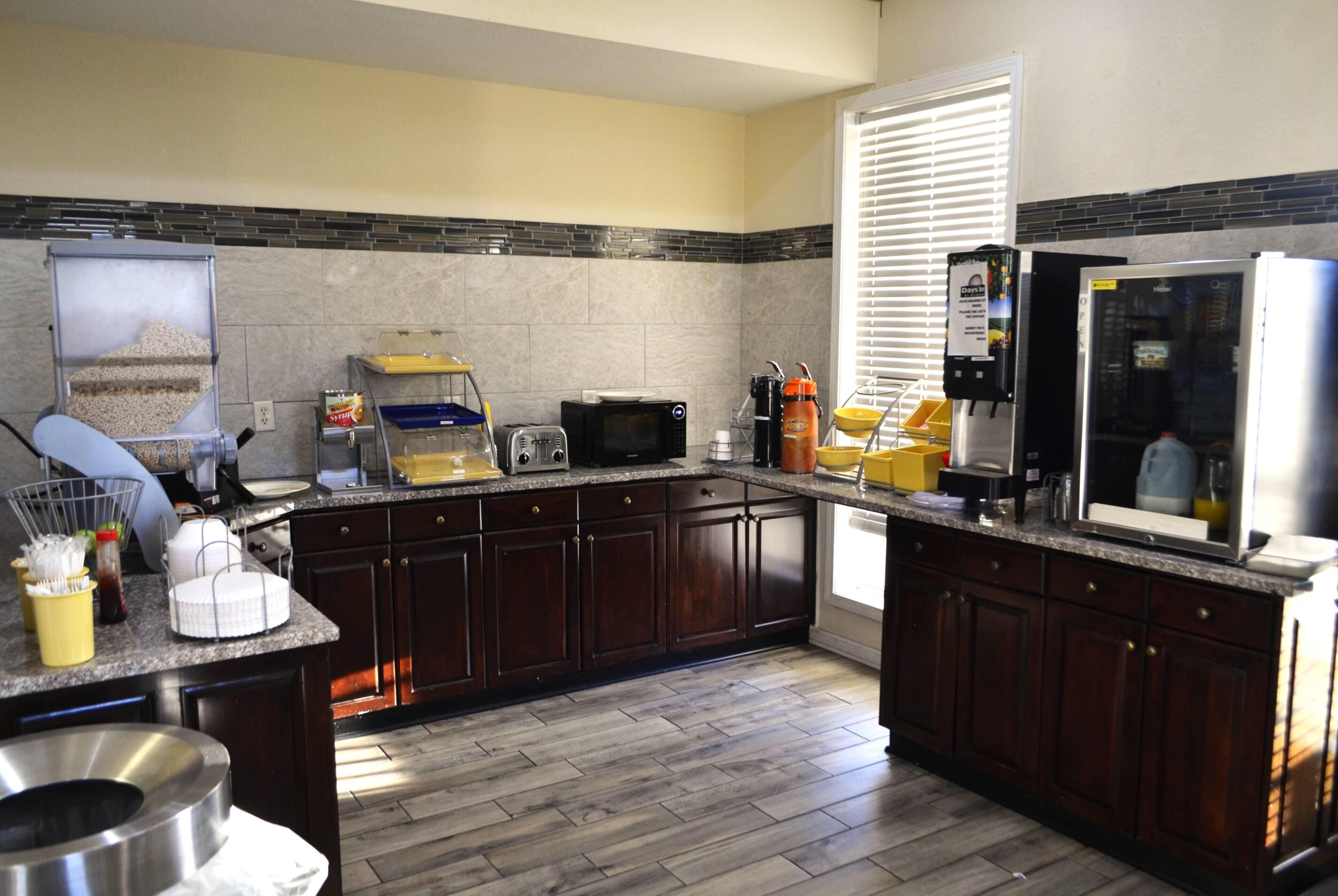 Una cocina moderna con armarios de madera oscura, encimera de granito, microondas, cafetera y refrigerador.