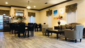 A spacious living room with a dining area, featuring a wooden floor, comfortable seating, a coffee table, and a fireplace. - Days Inn by Wyndham Trumann AR (Trumann)