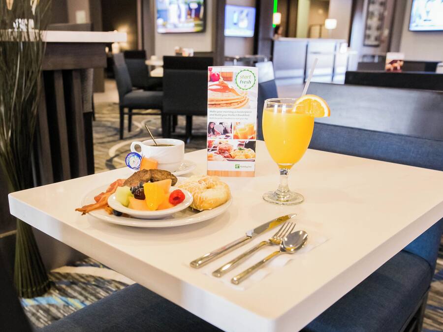 Ein Esstisch mit einem Teller Essen, einem Glas Orangensaft und einer Speisekarte.