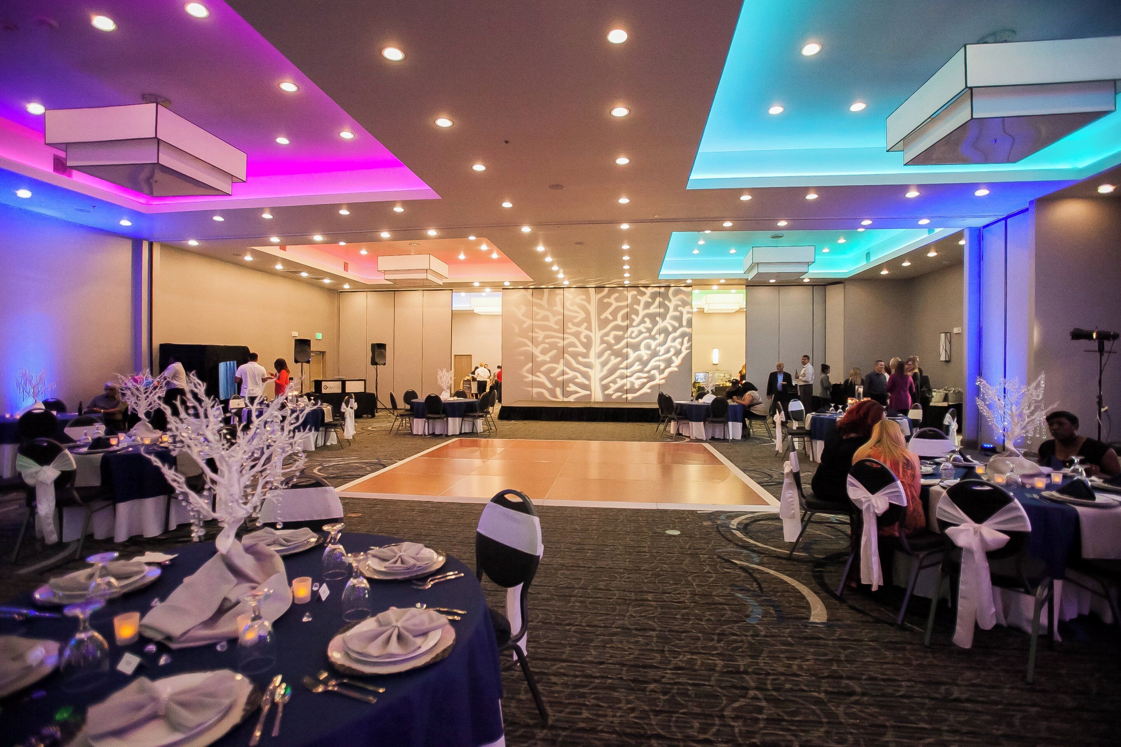 A banquet hall with round tables, chairs, and a dance floor.