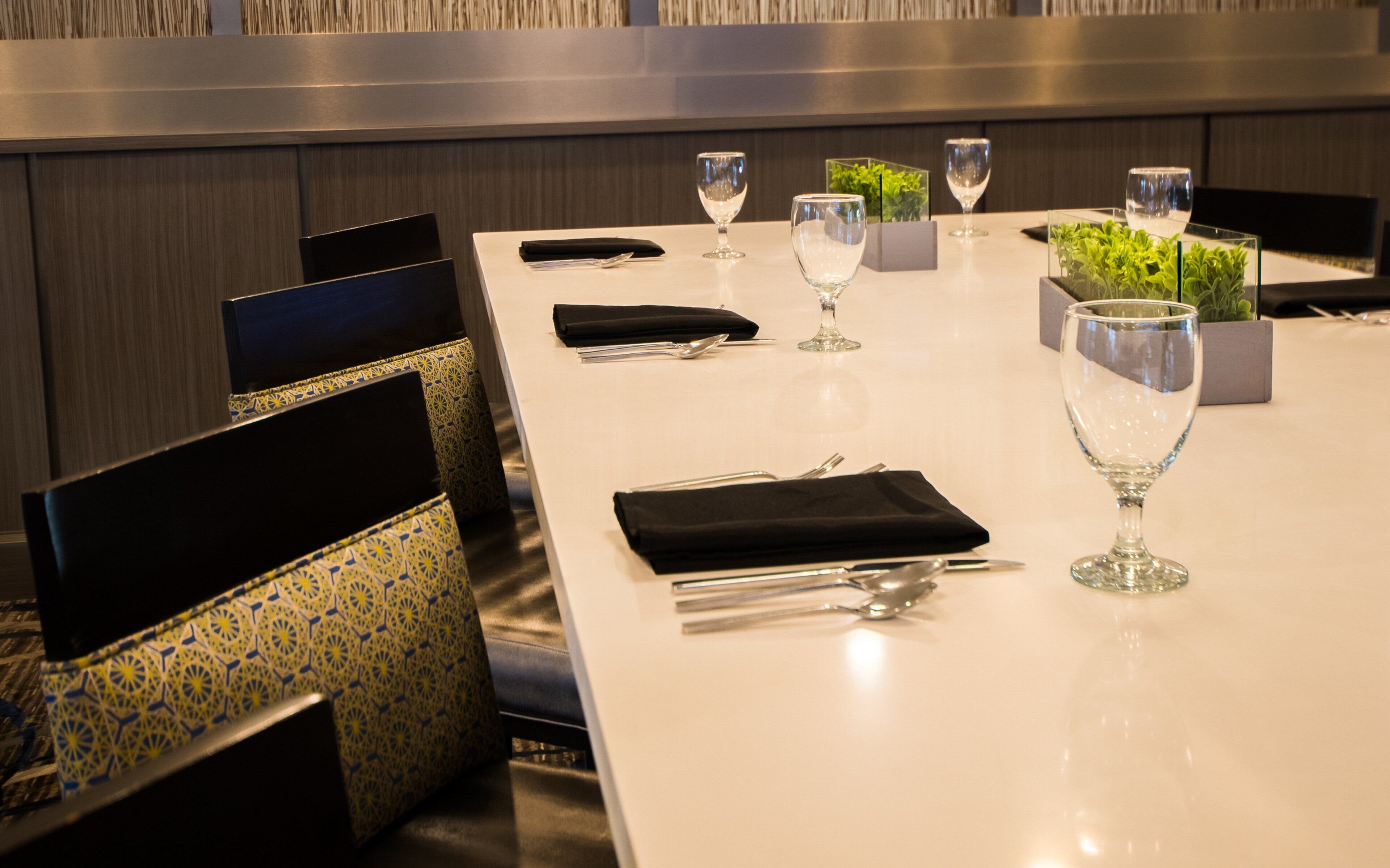A dining table set with cutlery, glasses, and a small plant.