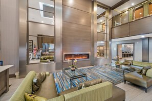A spacious living area with a large sofa, a glass coffee table, and a fireplace. - Holiday Inn Longview - North by IHG (Longview)